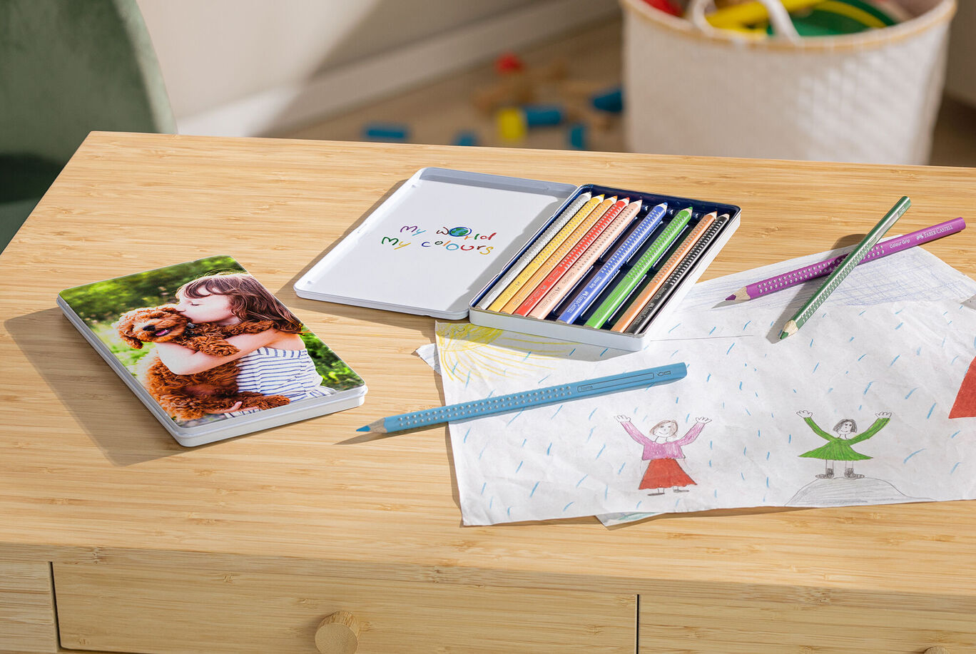 A loving scene with a CEWE photo book showing a cuddling person and an animal. Colored pencils and drawing sheets surround the photo book, inviting creativity.