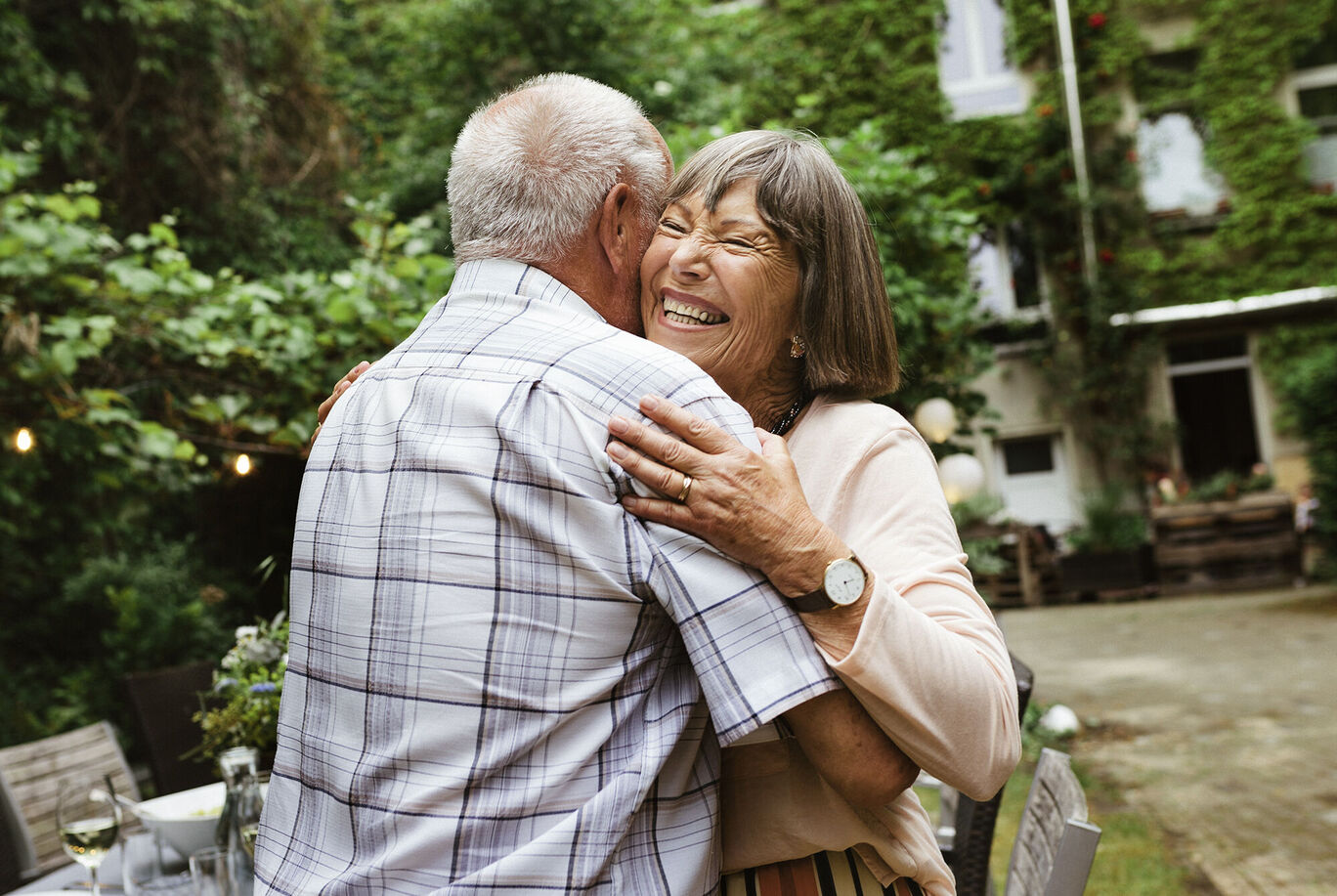Couple embracing warmly outdoors, surrounded by green nature.