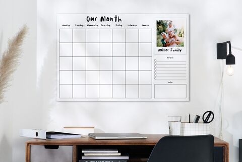 A large wall calendar with empty boxes for the weekdays. On the right, a photo of a happy family on a relaxing trip.