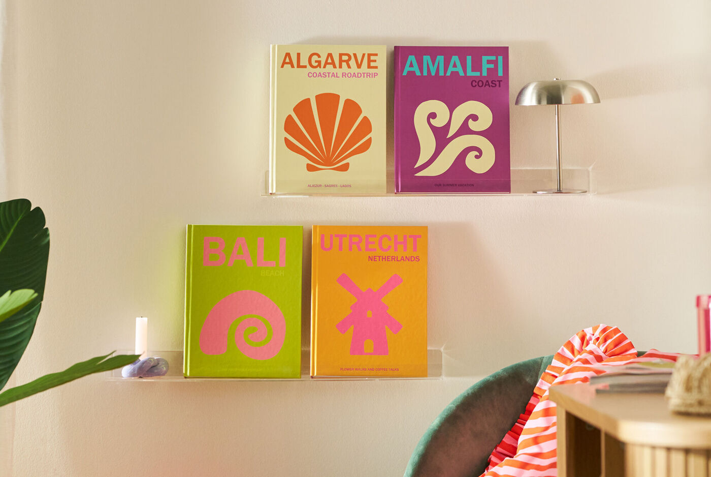 Four different travel coffee table books from different places are standing on a wall shelf in a colourful living room environment.