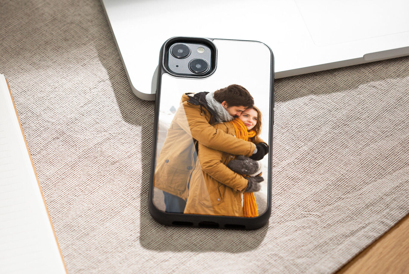 A couple lovingly embraces. The woman wears a yellow scarf. A gray sky is in the background.