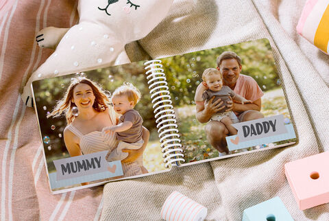 A happy family viewing a photo book outdoors with loving moments.