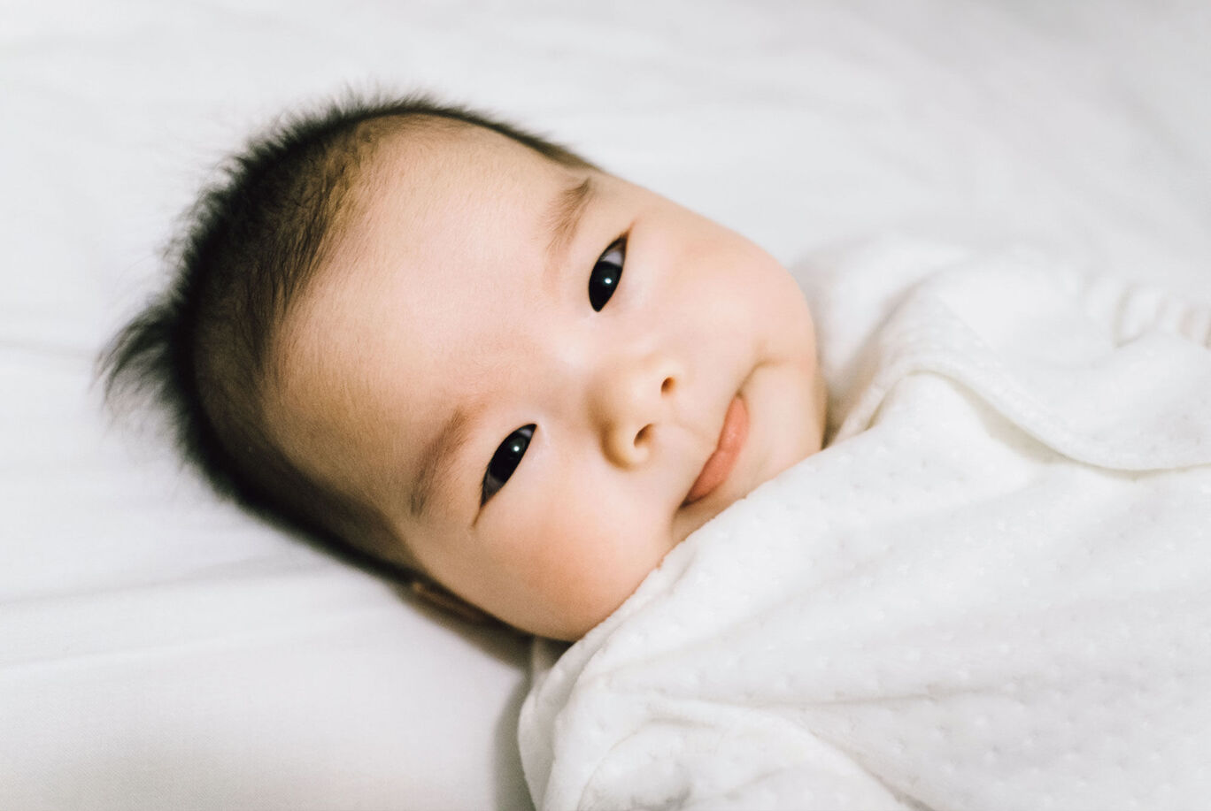 A sleeping baby in a white blanket, exuding a peaceful atmosphere.