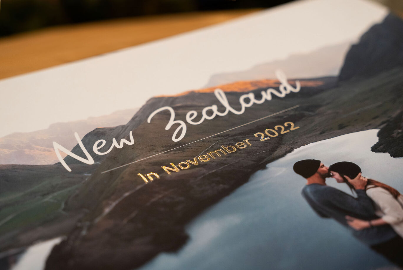 A beautiful photo book about New Zealand featuring a romantic kissing scene and landscape in the background, narrating vacation memories.