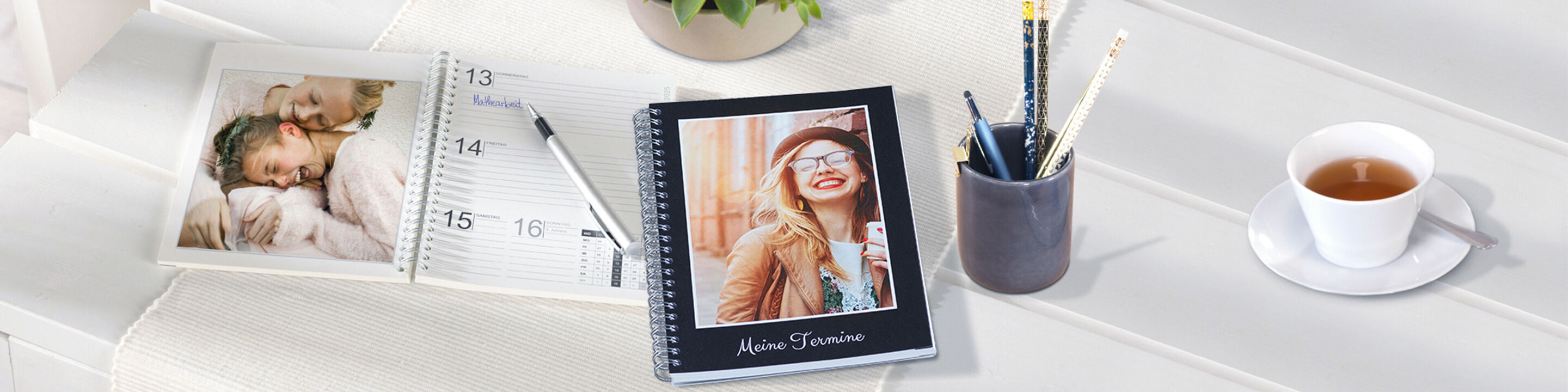 A beautiful photo calendar and a notebook with a personal photo on the table. A drink and pens create a creative mood.