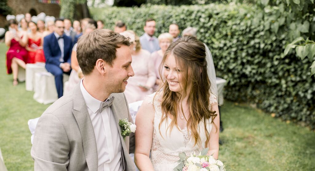 A happy couple at their outdoor wedding, surrounded by guests.