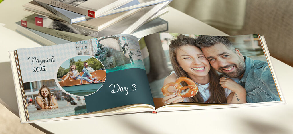 An open photo book with holiday photos from Munich 2022. One page shows happy moments by the water.