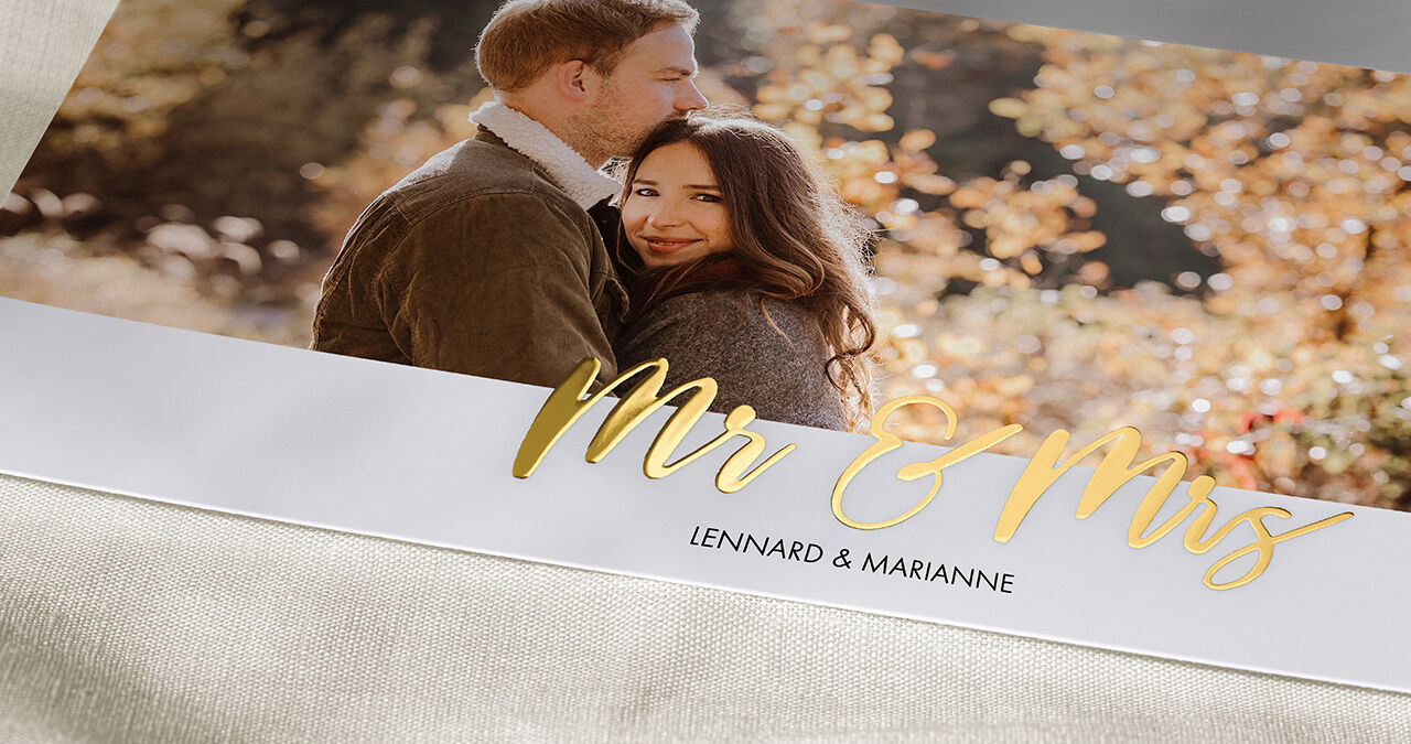 A couple looking lovingly at each other in an autumn setting with colorful leaves, surrounded by warm light.