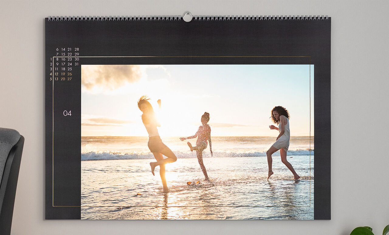 Three cheerful people dancing on the beach in the water at sunset
