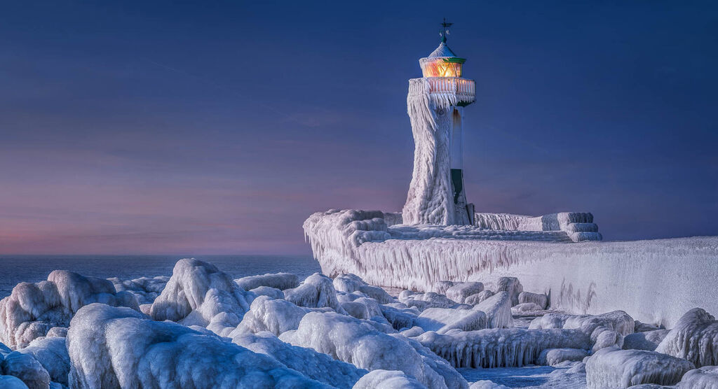 Icy lighthouse in winter scenery with frozen water