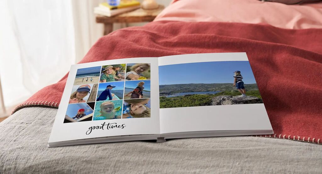 An open photo book on a bed, displaying various snapshots and the caption 'good times.'