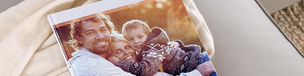 Smiling family warmly embraces on the cover of the CEWE photo book.