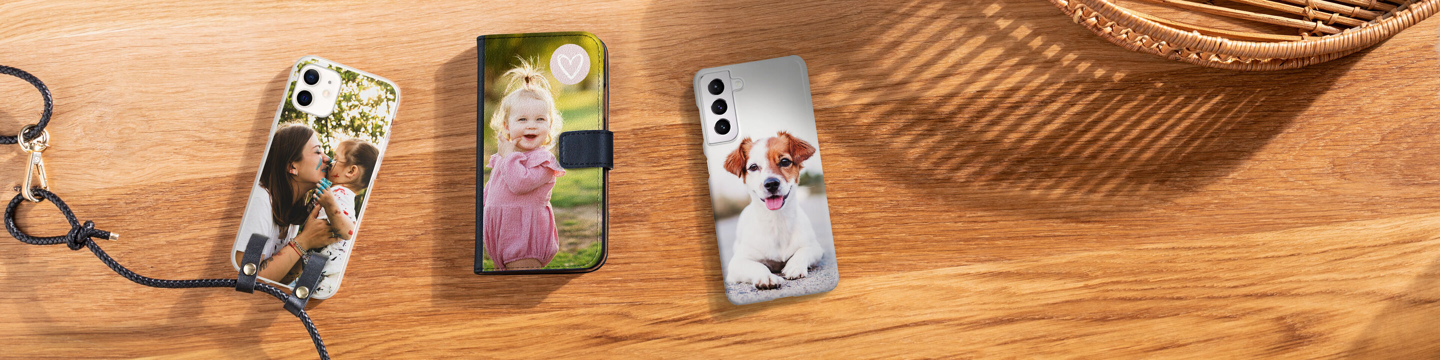 Three phone cases with personal photos on a wooden table.
