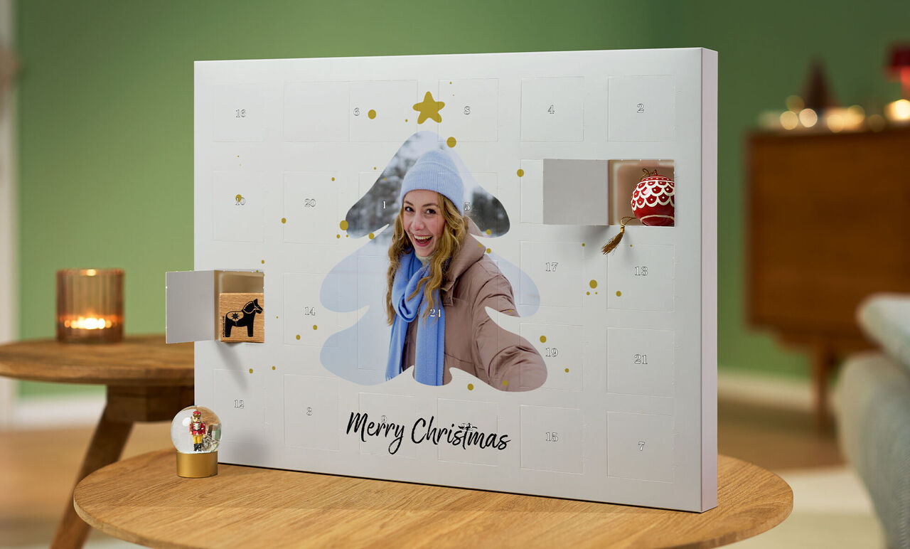 An opened advent calendar shaped like a Christmas tree with gifts and 'Merry Christmas' in a cozy room