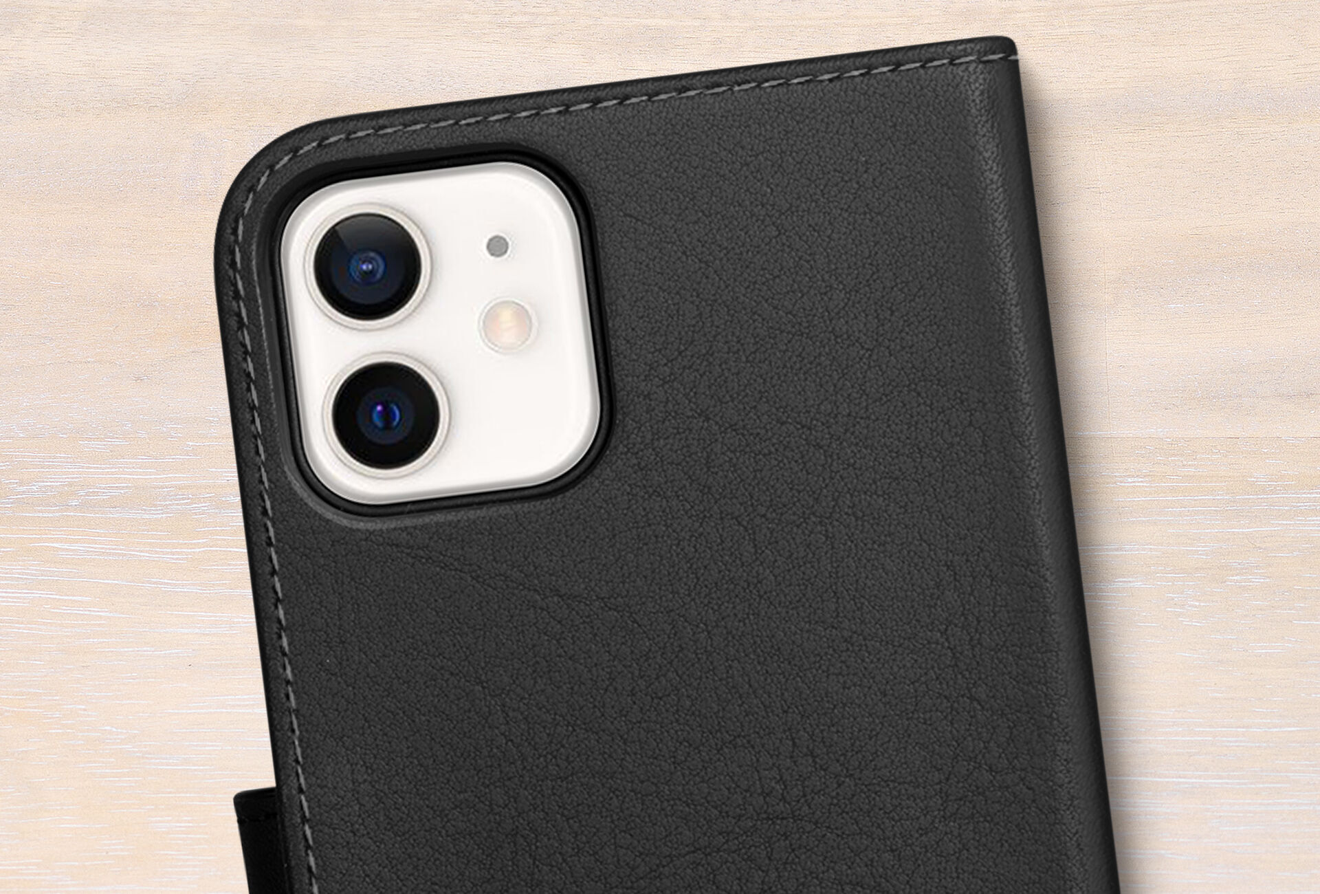 Black protective case for an iPhone 12 on a light surface, showcasing the device's camera modules.
