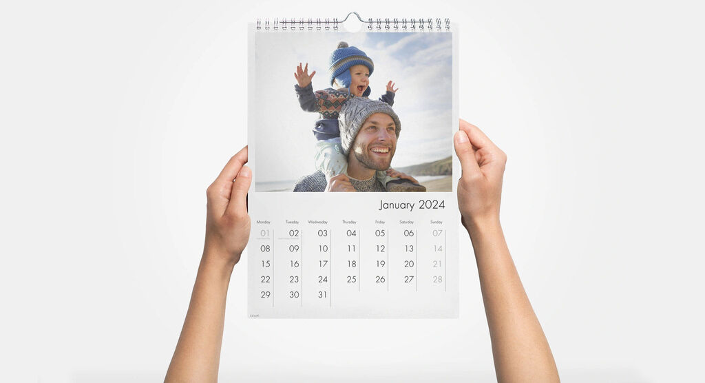 Child holds a calendar with a cheerful image, stating January 2024
