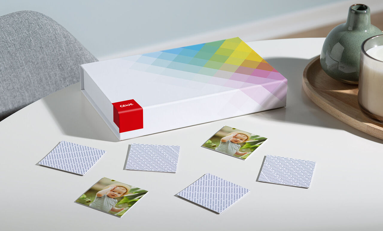 CEWE photo book on a table surrounded by small photos and a vase.