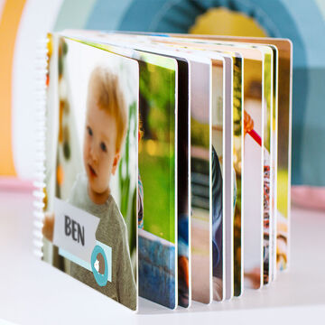 A CEWE photo book with colorful pictures open. In the middle, a child named Ben is visible.