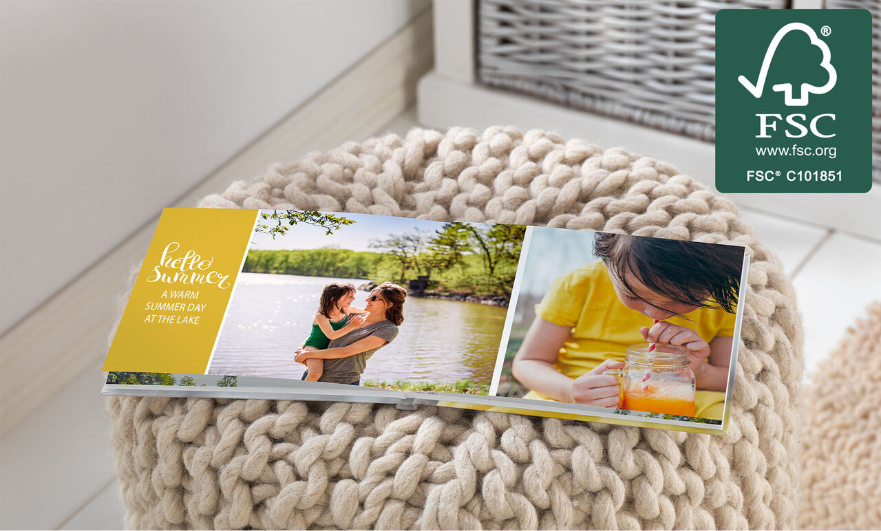 A family enjoys a warm summer day by the lake with a CEWE PHOTO BOOK on a stool.