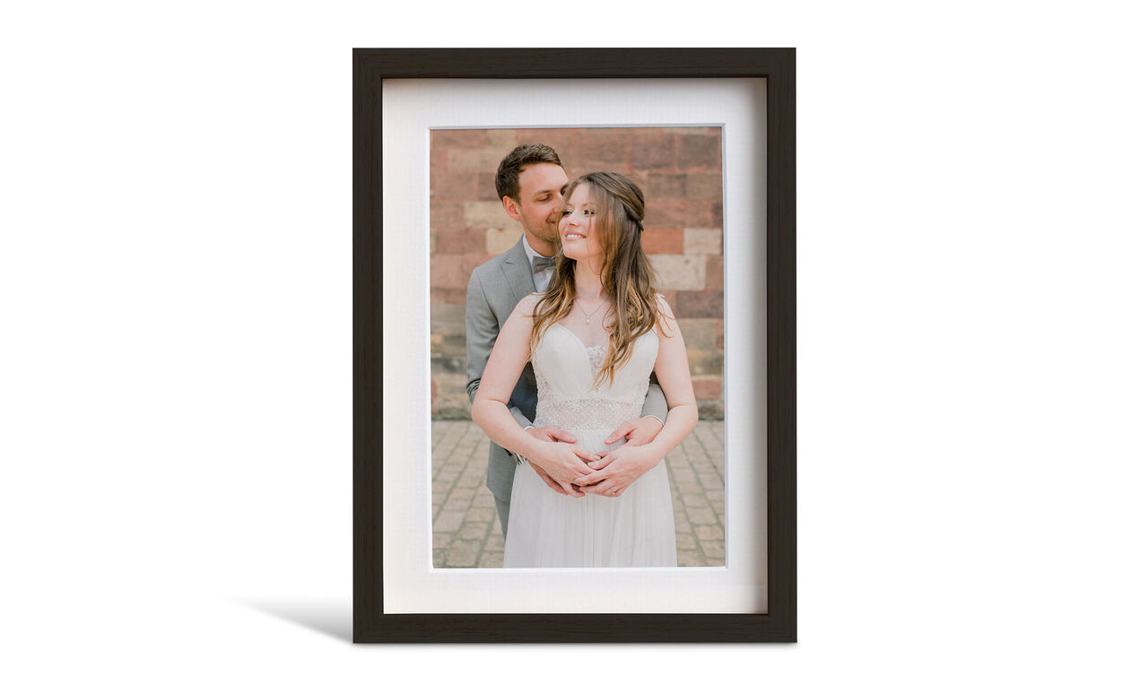 Couple embracing in front of a beautiful wall, the picture is in an elegant frame.