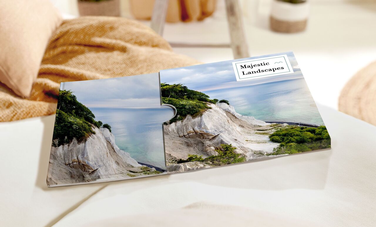 A beautiful CEWE photo book featuring a landscape photo of cliffs and sea, opened on a table.