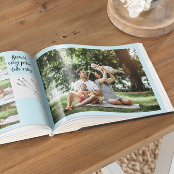 A family reads together in an open photo book on a wooden surface