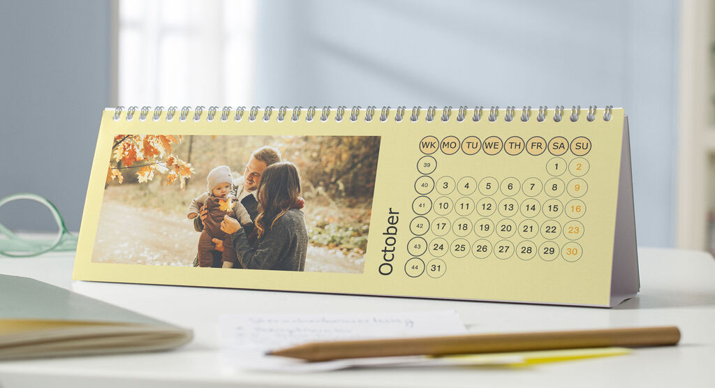A yellow desk calendar shows a warm family picture in October.