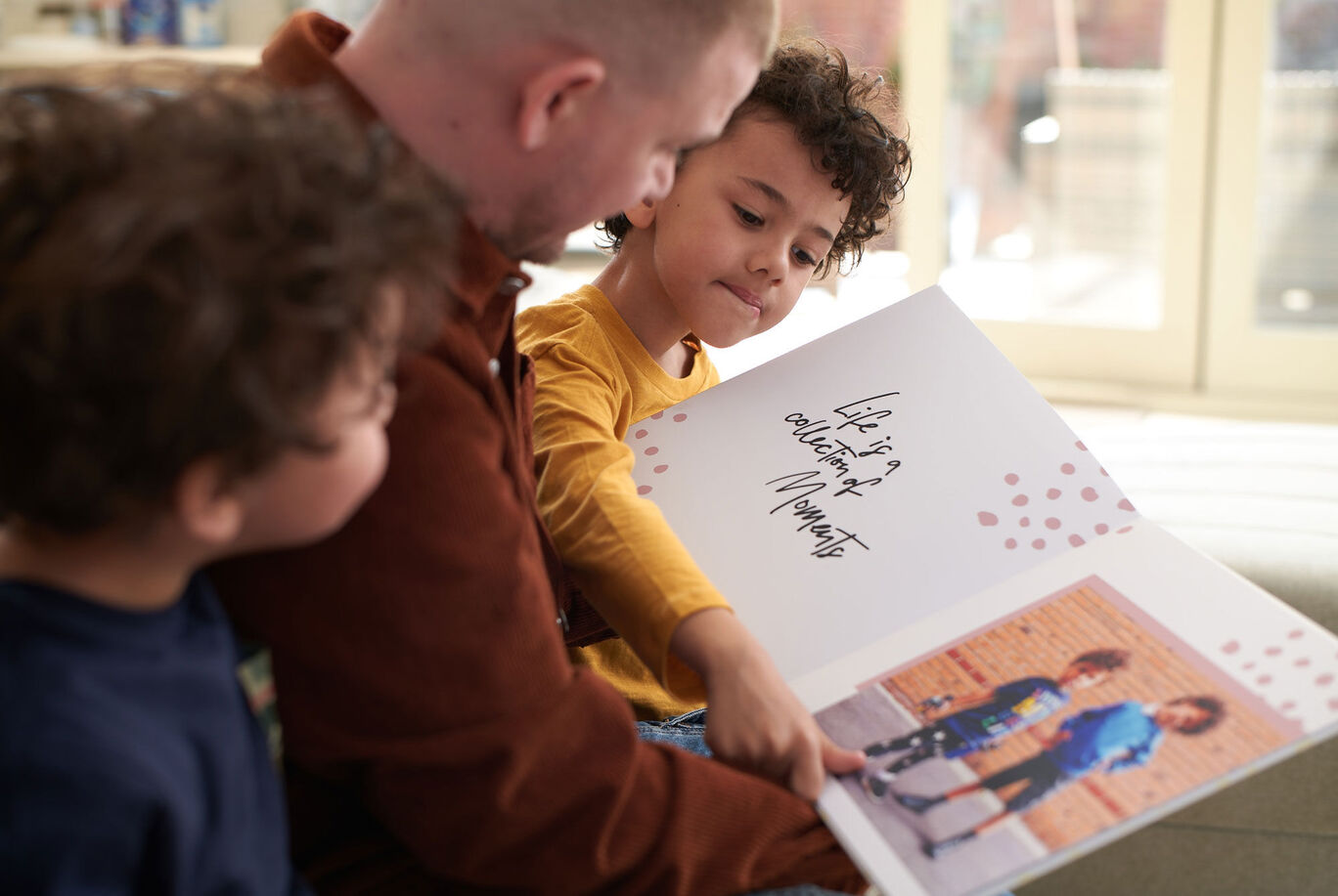 A loving scene where an adult looks at a photo book with children while smiling.