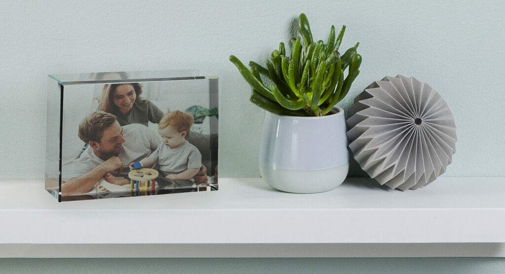 A loving family photo in a glass block shows a child playing with a toy while an adult sits nearby. A green plant and a decorative item on a shelf create a cozy atmosphere.