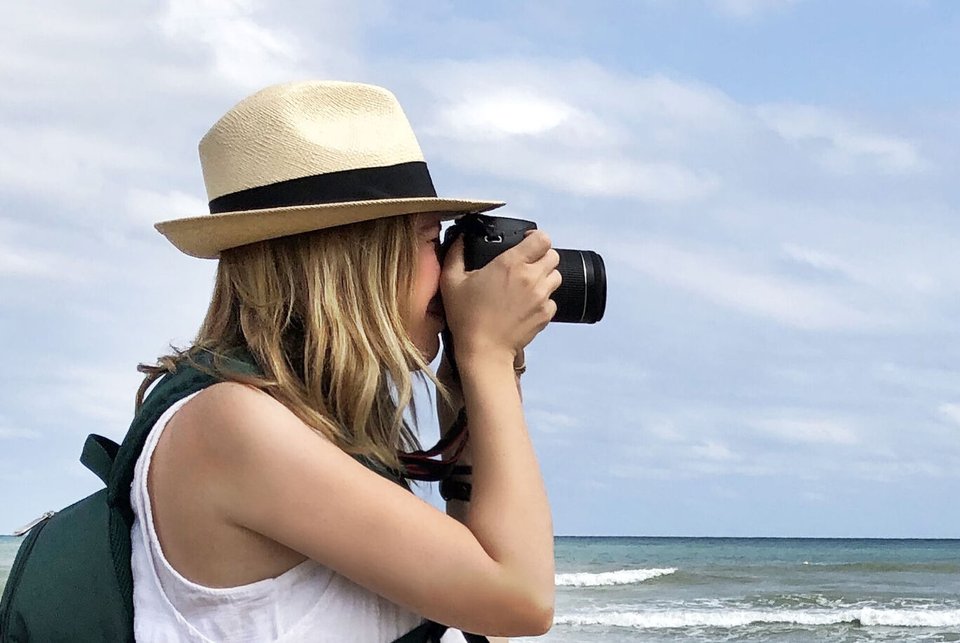 A woman with a camera at the beach, gazing at the water