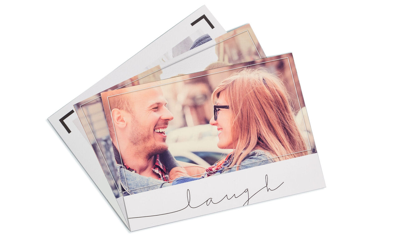 Two people stand close together and laugh friendly.