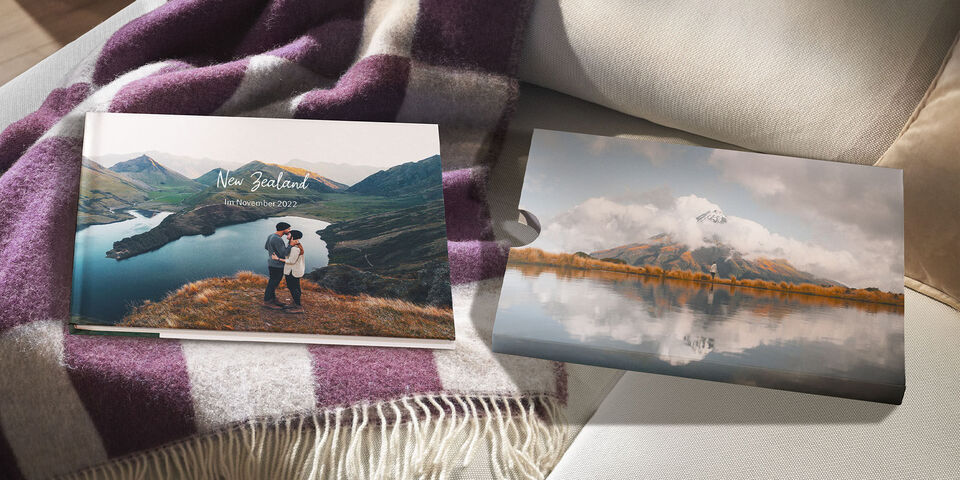 Two CEWE photo books showcase memories of New Zealand on a cozy sofa.