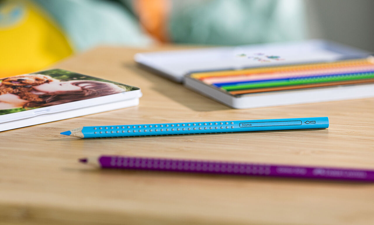 Colorful pens on a wooden table with a photo book in the background.