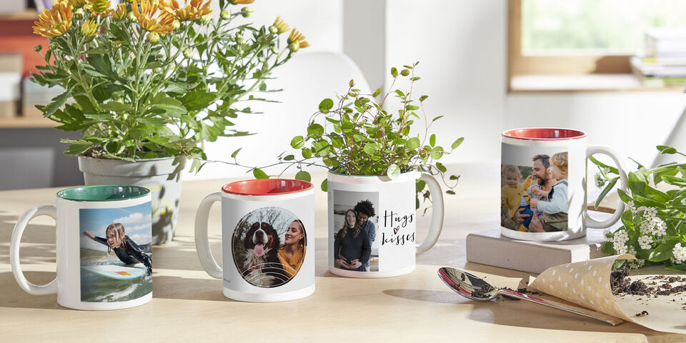 Four personal mugs with photos of friends and plants on a table