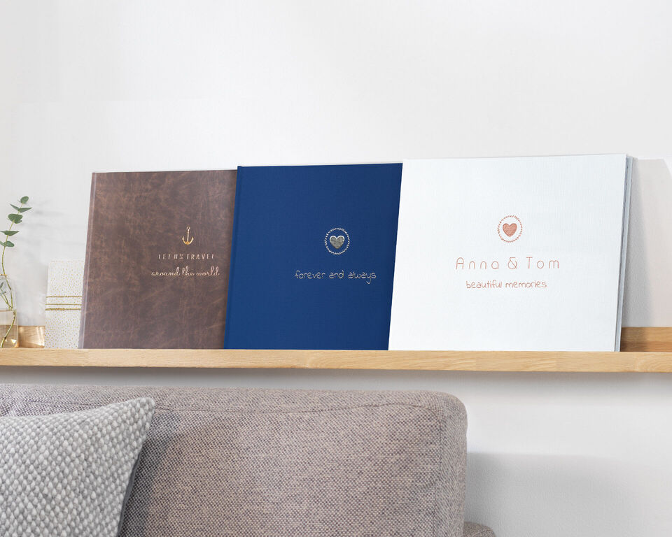 Three different photo books on a shelf. Each has different cover designs in brown, blue, and white.