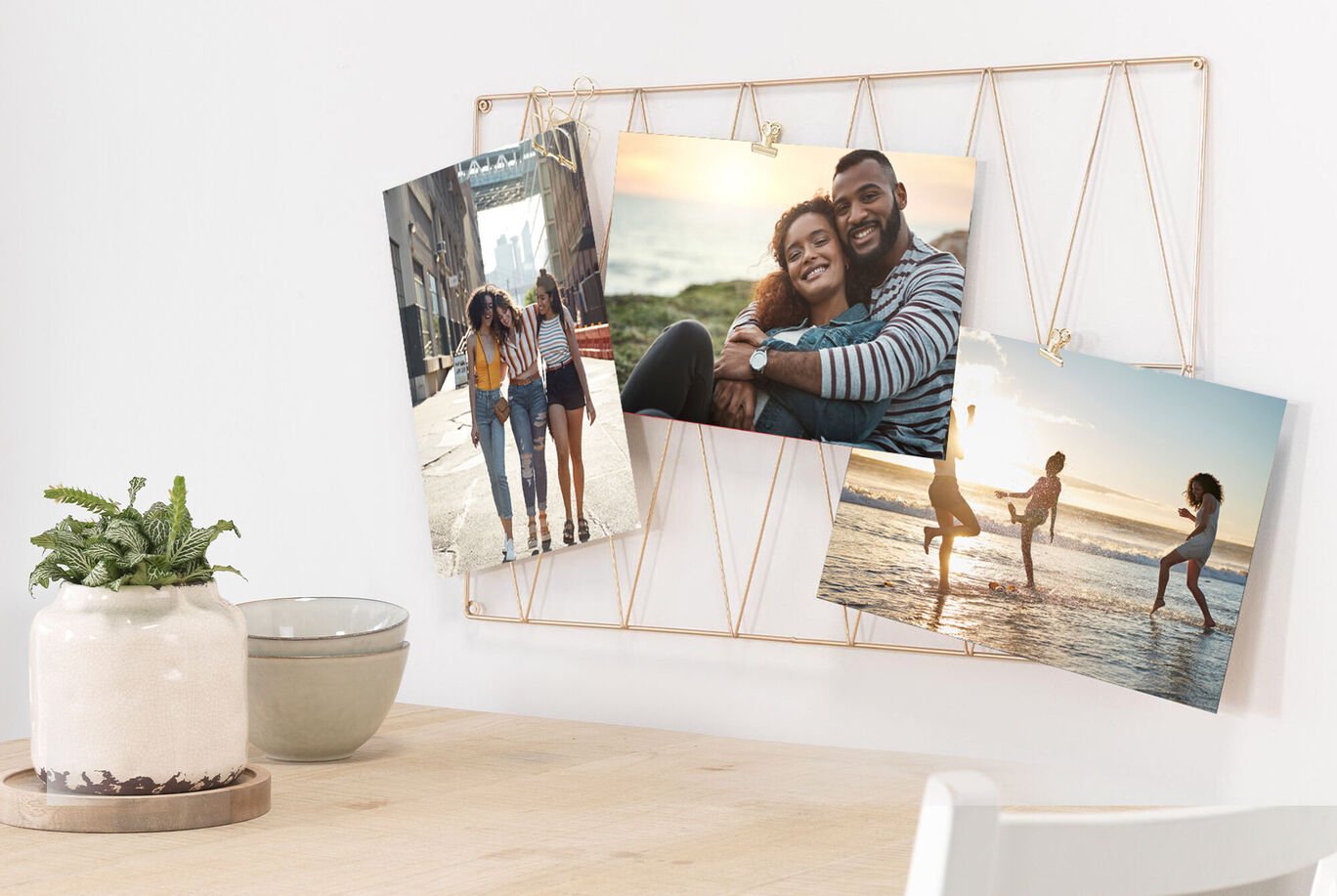Three photos on a wire wall with plants in the background