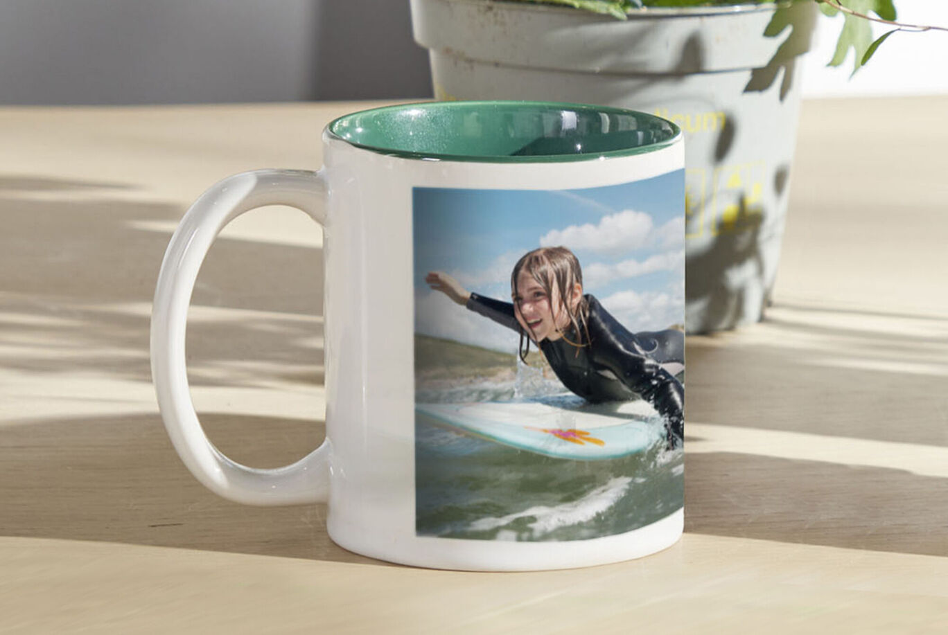 Mug with a child surfing on a surfboard, with waves and sky in the background.