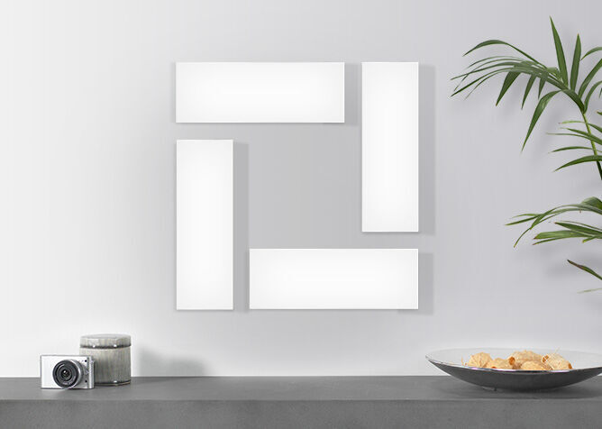 Five empty picture frames in different sizes on a wall, with a camera and a bowl of snacks on a table.