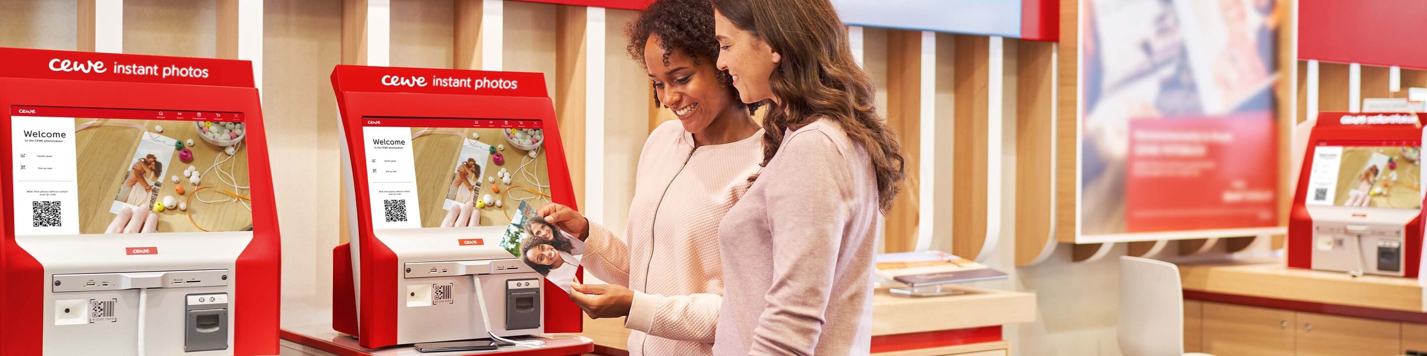 Two people use a digital photo kiosk at CEWE