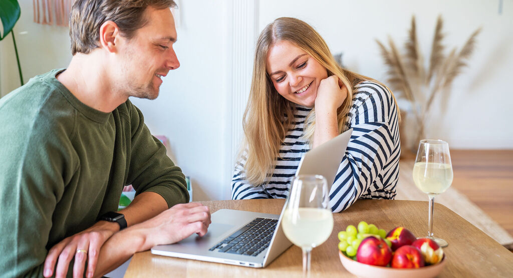 Two people at a table with a laptop and fresh fruit.