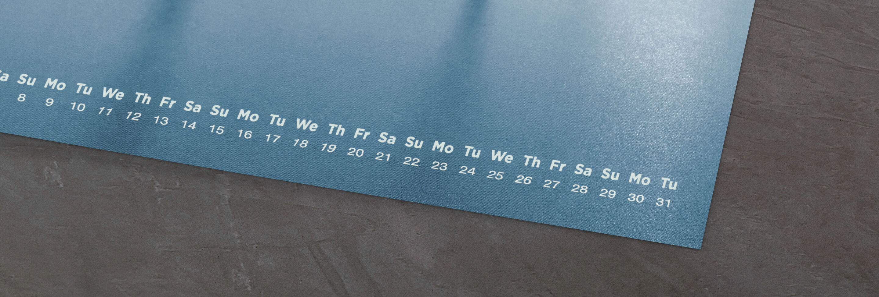 Close-up view of a CEWE photo calendar with blue backgrounds and a clear weekday layout