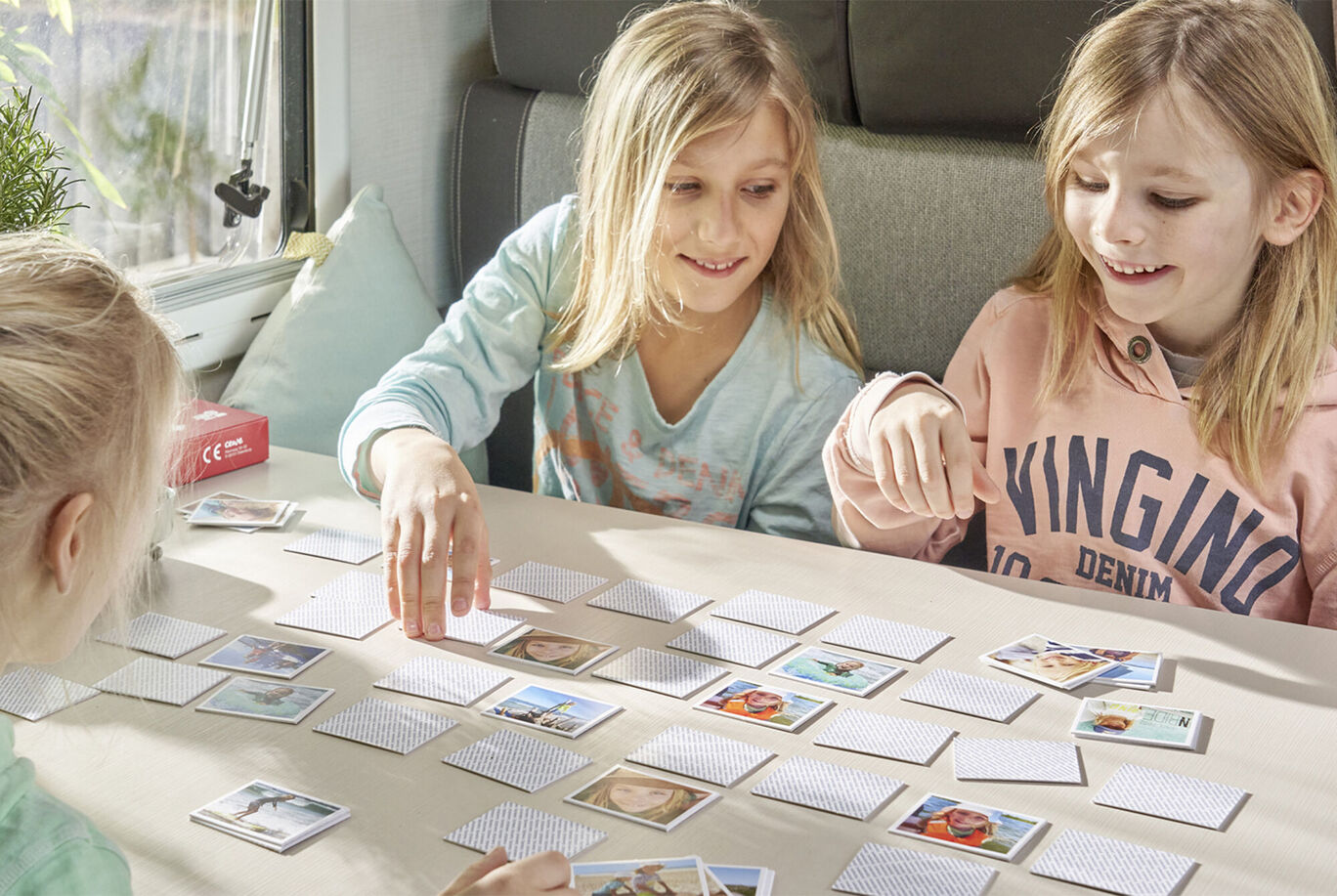 Two children play a memory game together, laying cards on a table.