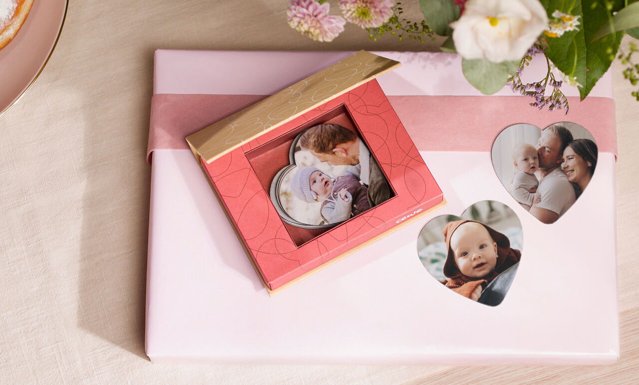 A beautiful red gift with photo cards is lovingly presented, surrounded by flowers. Perfect for giving memories.
