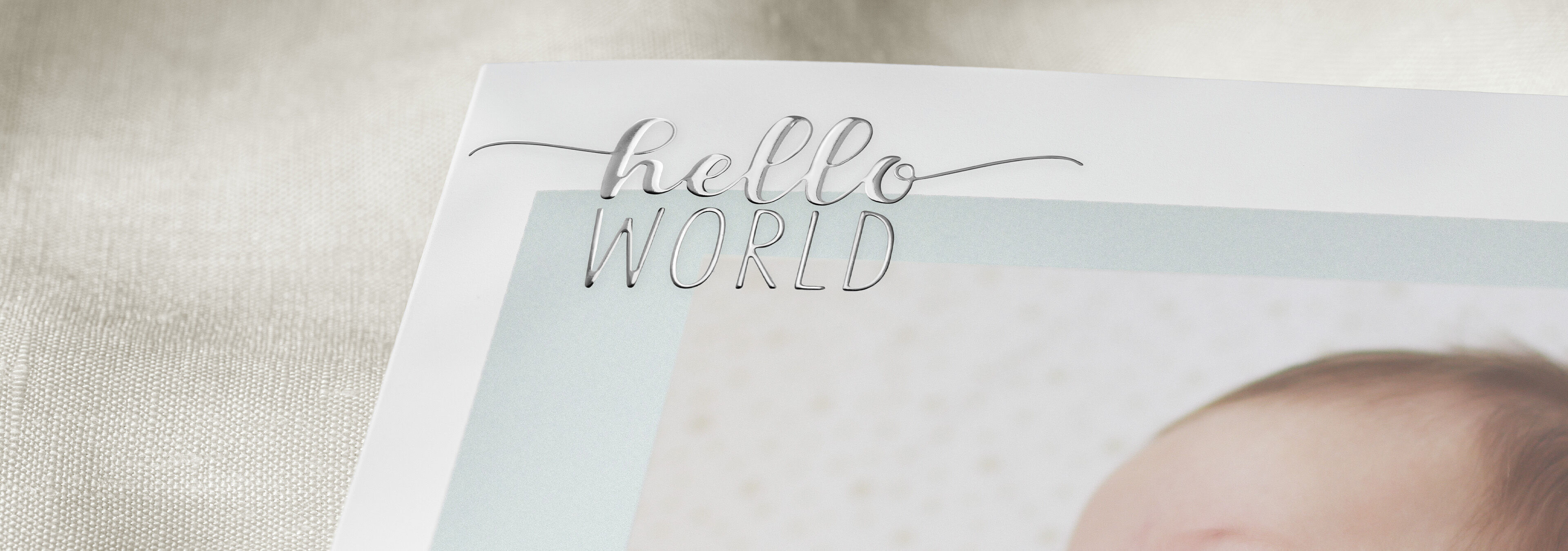 The title 'hello WORLD' decorates a picture of a newborn in a photo book.