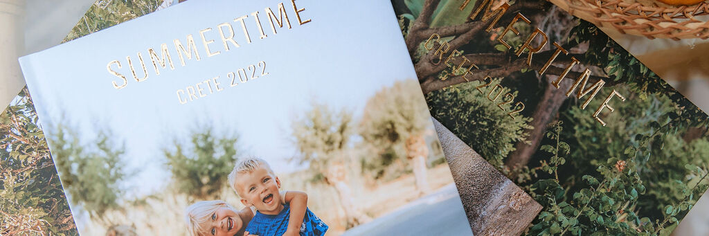 Three CEWE photo books on a table with a child and an adult in the foreground.