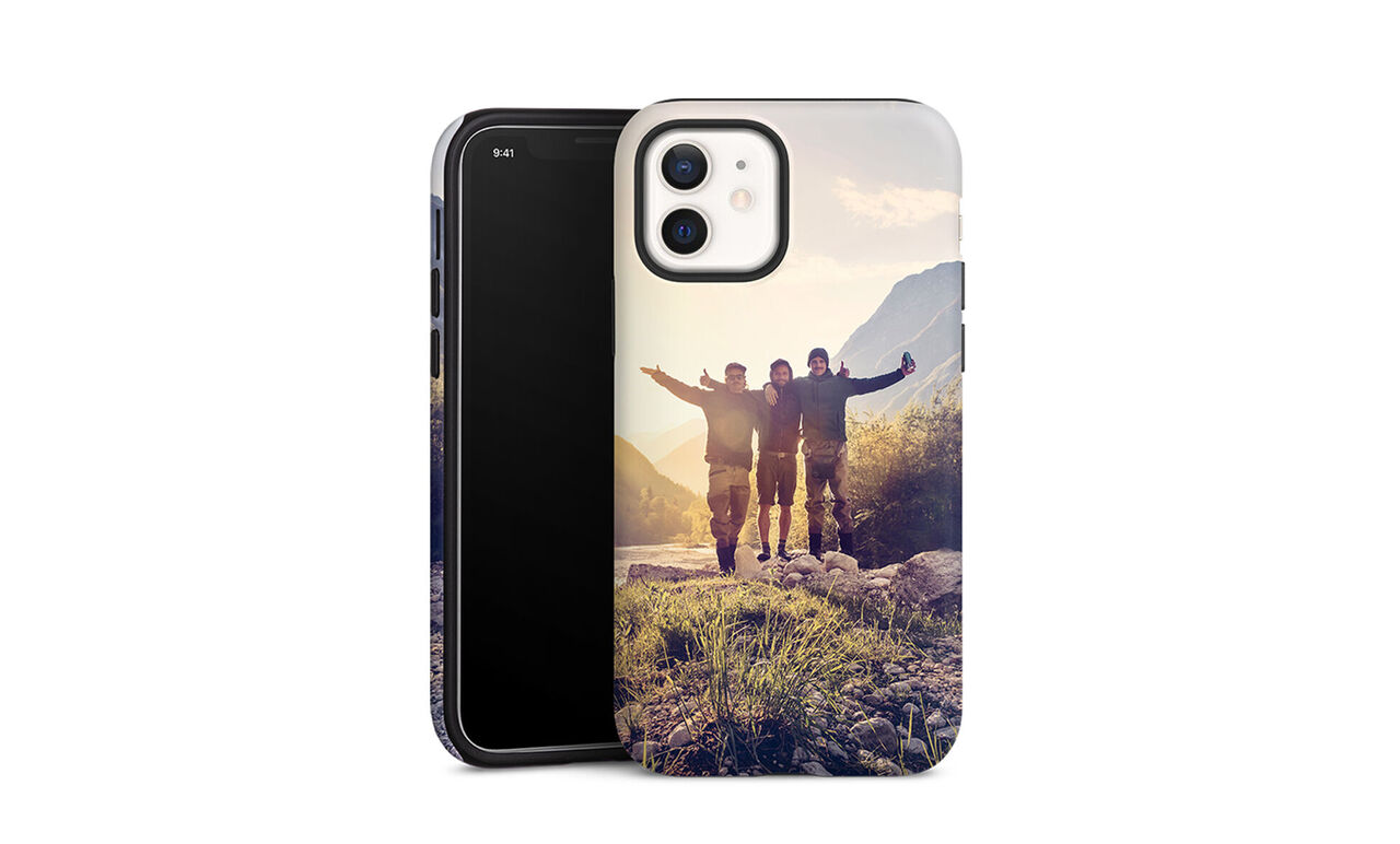 Three cheerful people hug in front of a picturesque mountain landscape, expressing joy in togetherness.