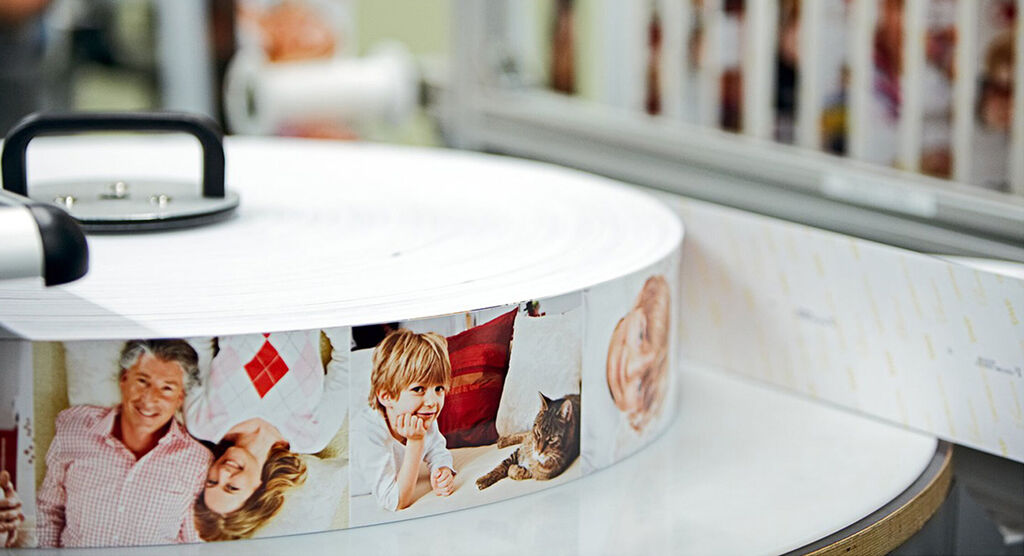 Stacked CEWE photo book spines featuring images of family and friends.