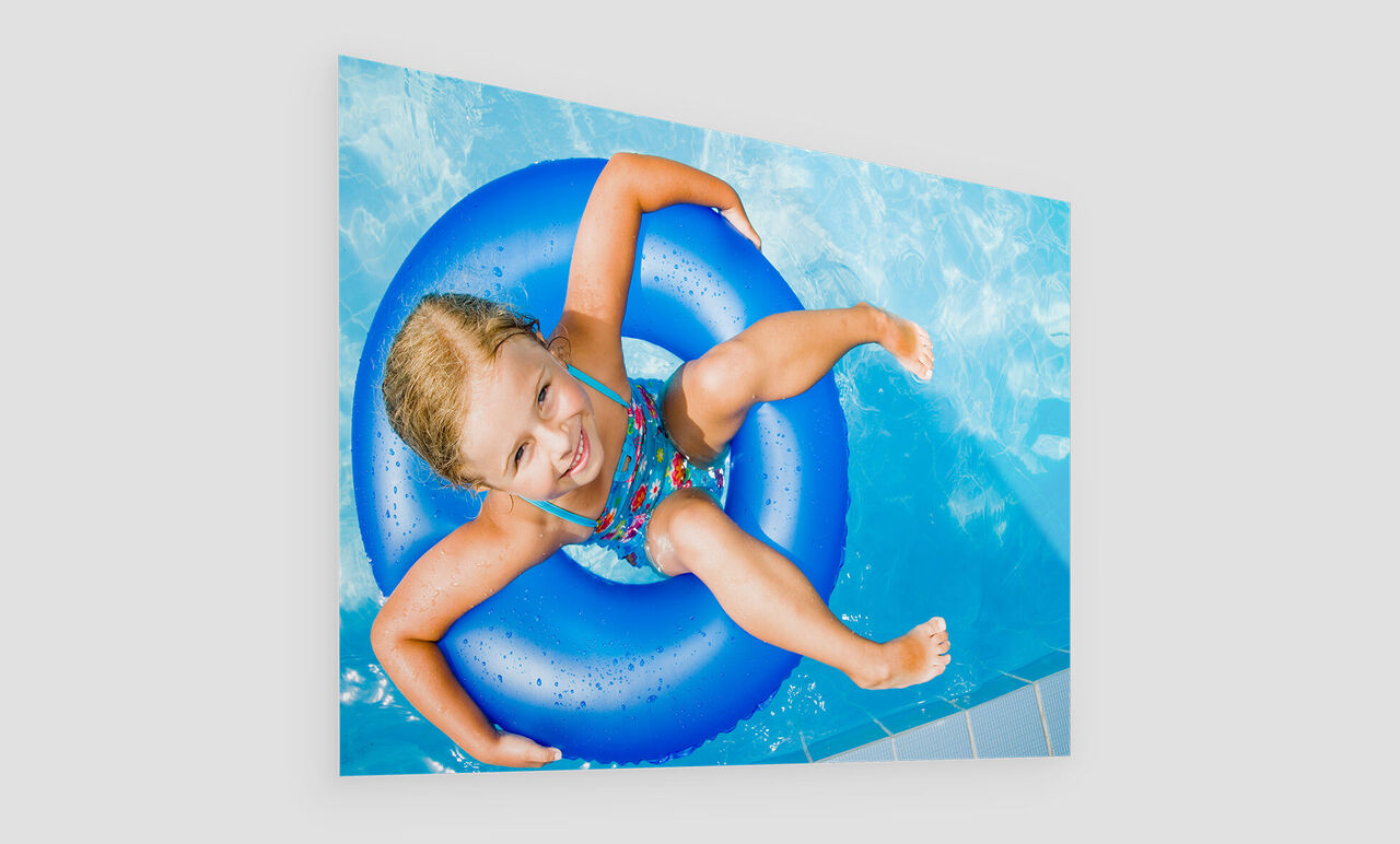 A child happily plays with a blue swim ring in the water.