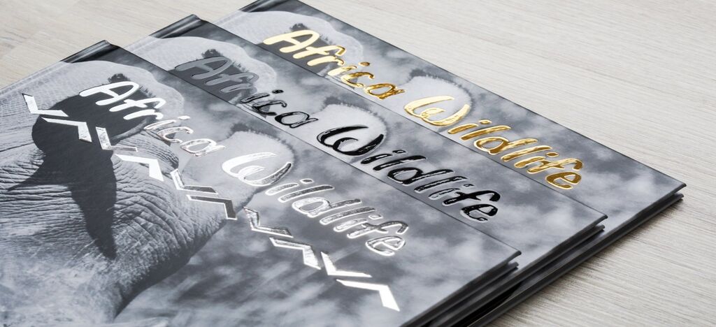 Three stylish CEWE photo books titled 'Africa Wildlife' on a light wooden surface.