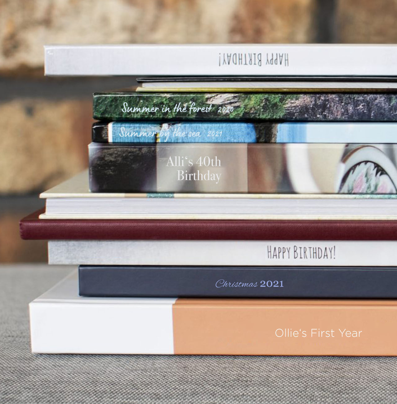 A stacked collection of photo books, each with a personalized title, on a table.